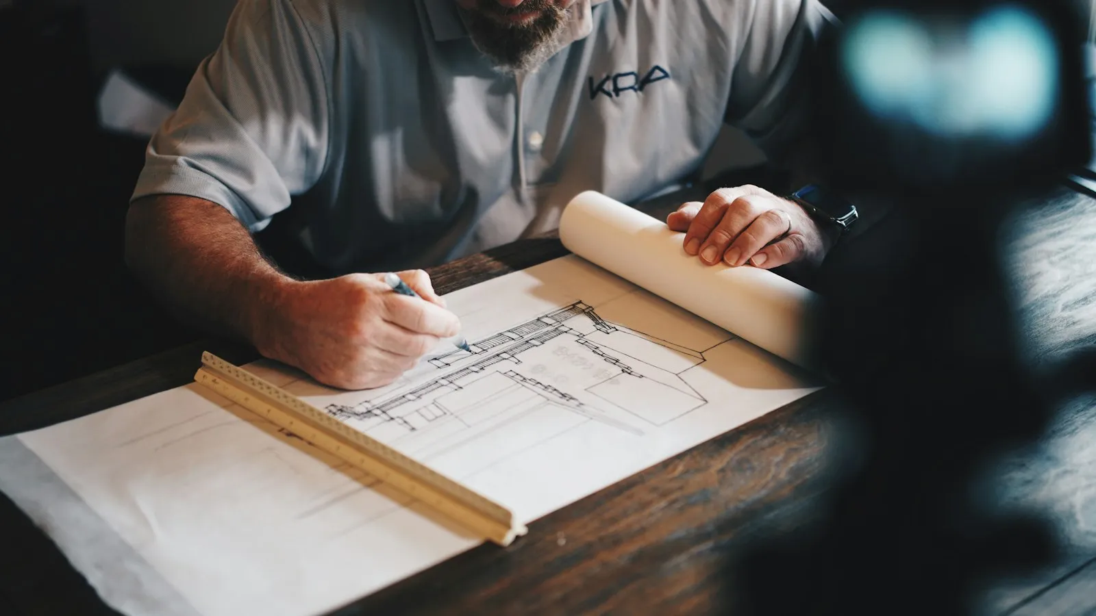 Artisan annotant un plan de rénovation sur une table de travail