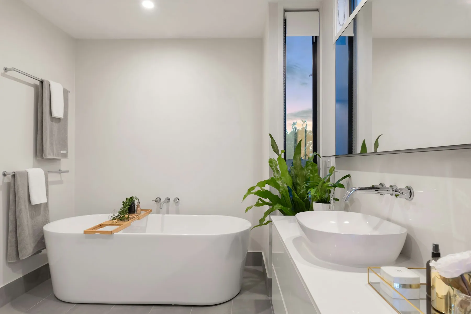 Salle de bains blanche avec baignoire îlot, vasque ronde et plante verte