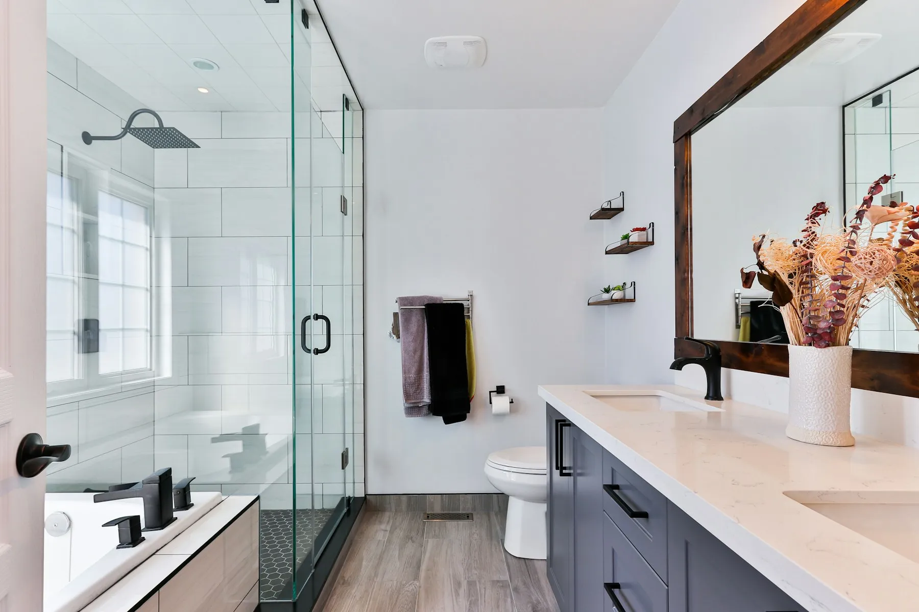 Salle de bains avec douche vitrée, faïence blanche et meuble vasque sombre