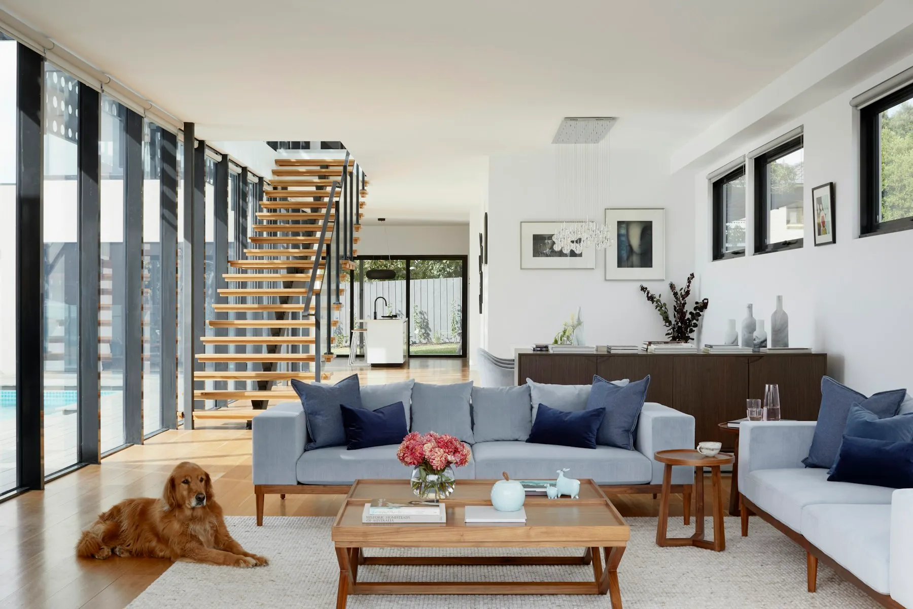 Séjour lumineux avec canapé gris, table basse en bois et escalier à l'arrière-plan